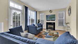 A living room with a fireplace, blue sofas, and a TV.
