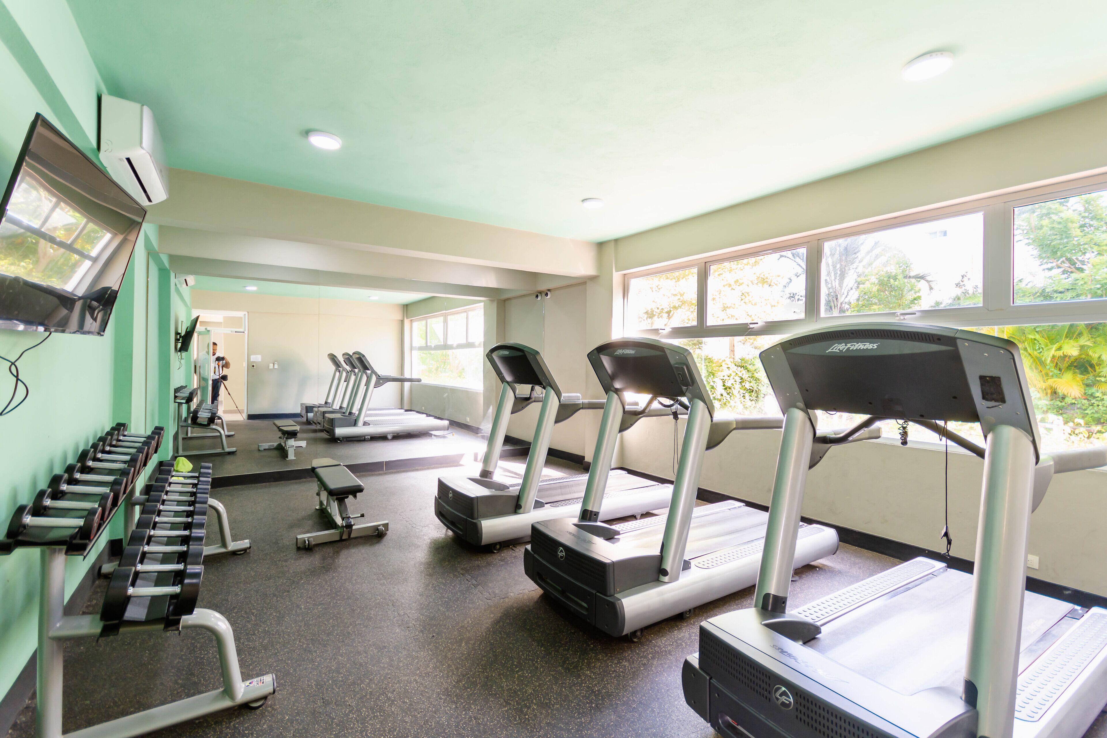 A gym with treadmills, weight machines, and a mirrored wall.