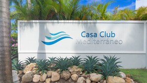 Schild für Casa Club Mediterraneo mit einem angelegten Garten, der Felsen und Pflanzen zeigt.