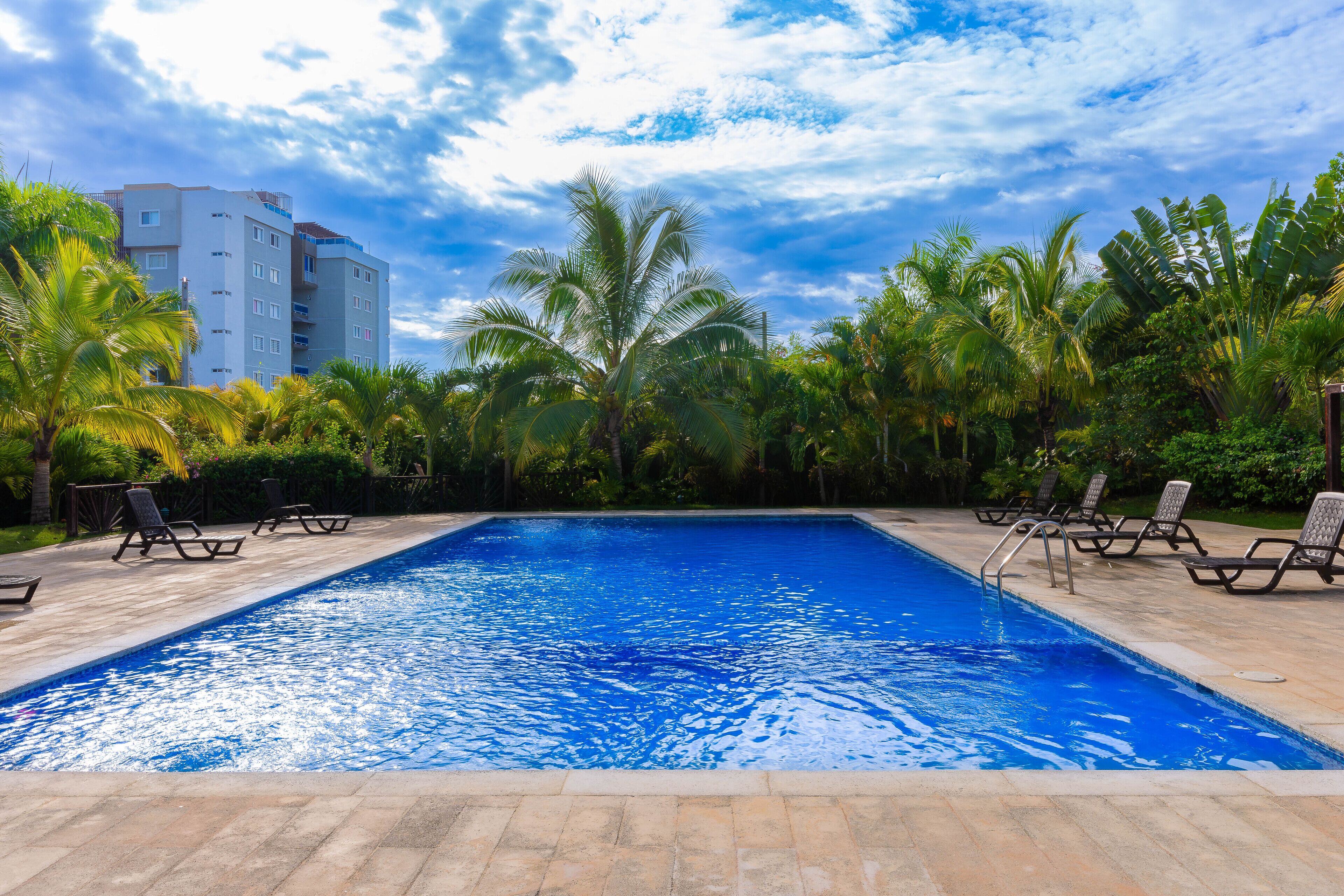 Una piscina al aire libre, sillones reclinables de piscina