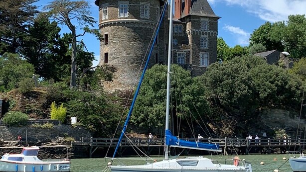 Un castillo con torre, rodeado de agua y barcos.