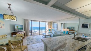Habitació d'hotel moderna amb cuina, zona de dinar i un balcó amb vista a l'oceà.