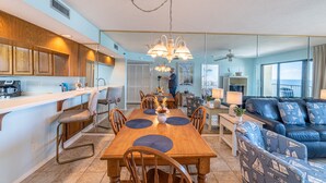A modern kitchen with wooden cabinets, a dining table with placemats, and a bar area.