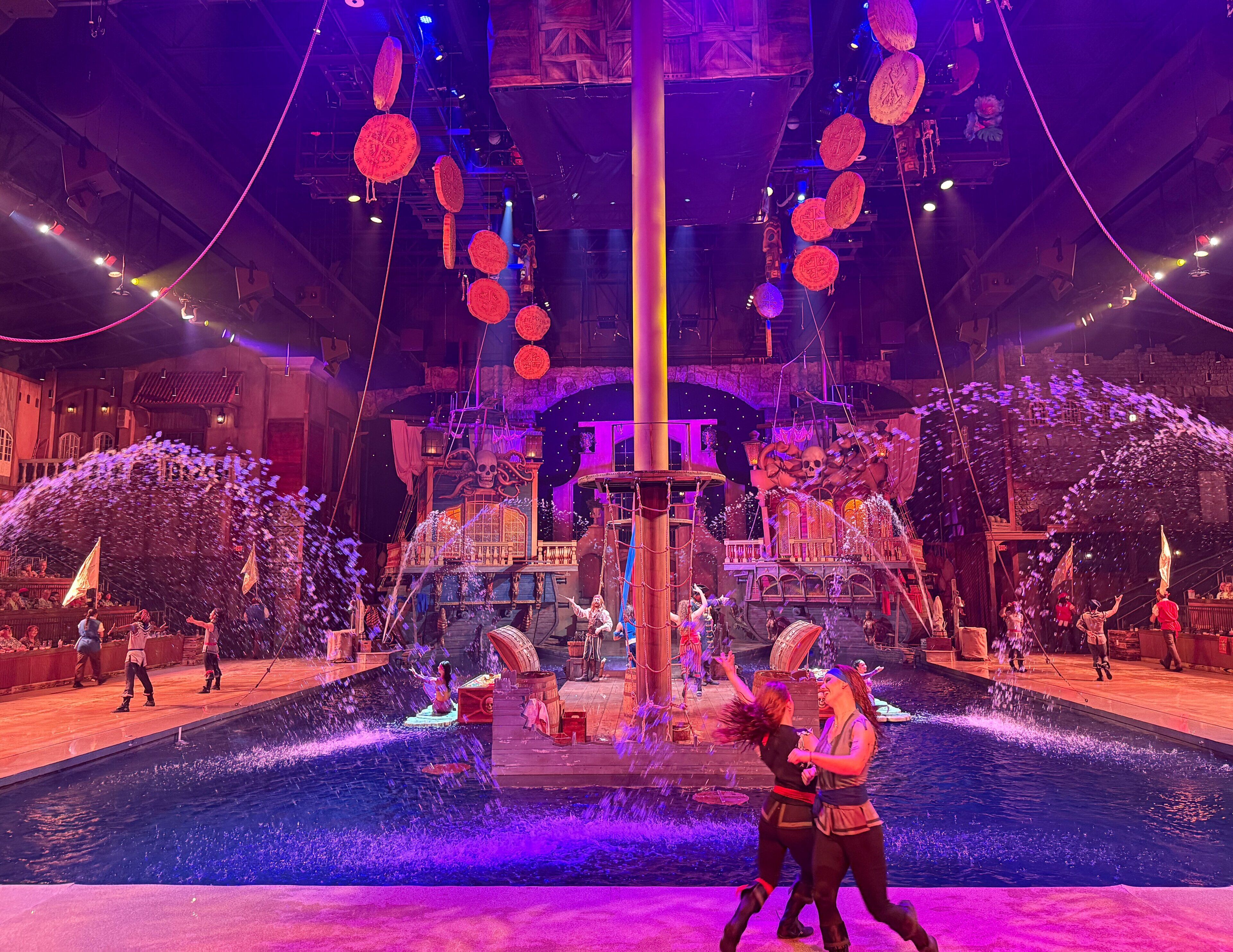 A stage with a water fountain, performers, and a large backdrop.