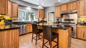 A modern kitchen with wooden cabinets, stainless steel appliances, and a central island with bar stools.
