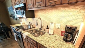 A kitchen with granite countertops, stainless steel sinks, and a coffee maker. - New Lakefront Condo! Great Views! Pool/Hot Tub! (Whitefish)