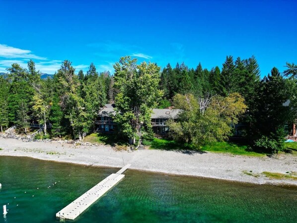 Une propriété située au bord d’un lac, dotée d’un quai, entourée d’une forêt dense et comprenant deux maisons.