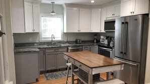 Una cocina moderna con armarios grises, electrodomésticos de acero inoxidable y una isla de madera.