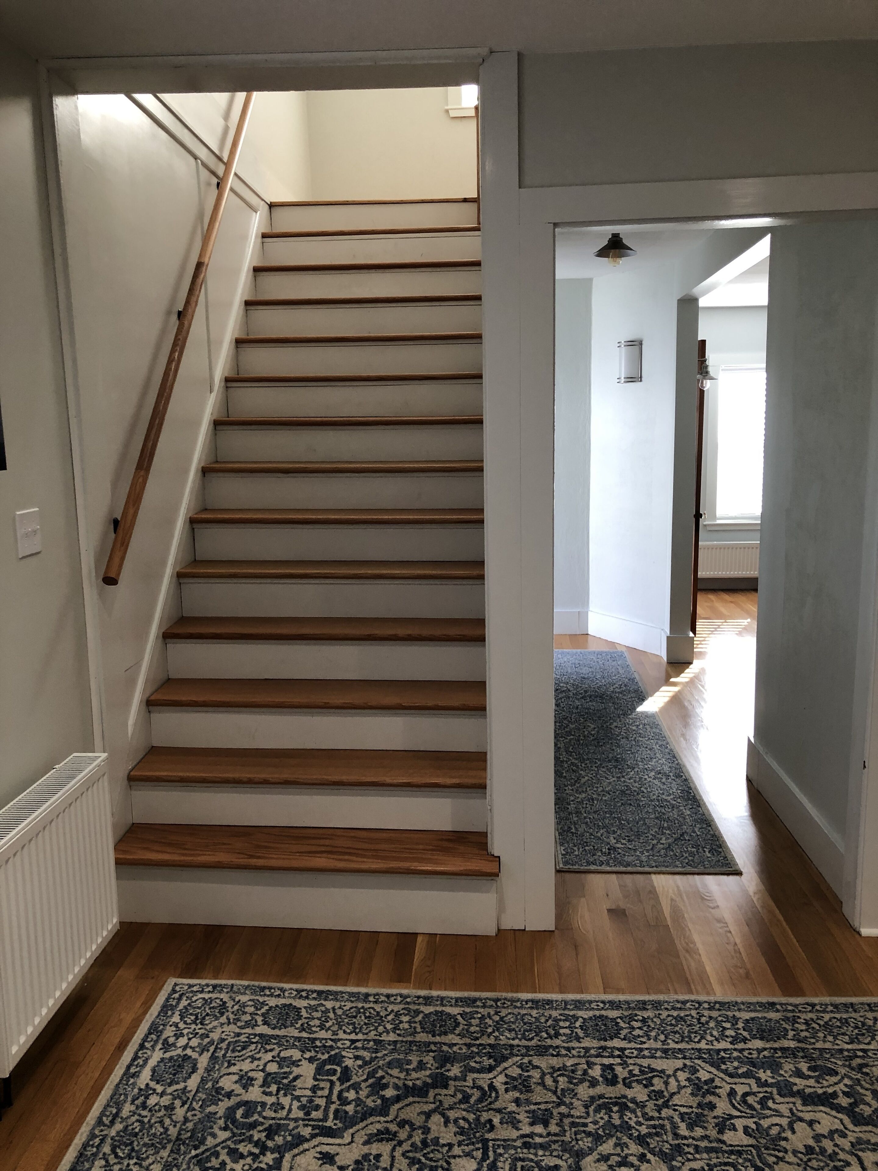 Eine Treppe mit Holzboden und Handlauf, die zu einer Empfangshalle mit einer Tür führt.