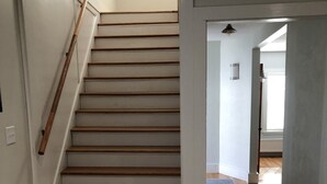 Una escalera de madera con barandilla, que conduce a un rellano con una puerta.