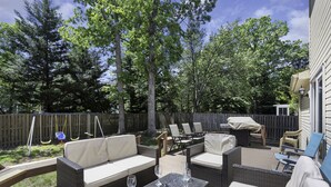 Une terrasse extérieure avec des meubles en osier, un barbecue et une balançoire.