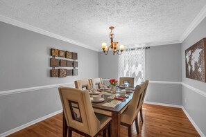 Comedor con una mesa de madera dispuesta para seis personas, rodeado de sillas color beige.