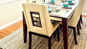 Une salle à manger avec une table rectangulaire dressée pour six personnes, entourée de six chaises.