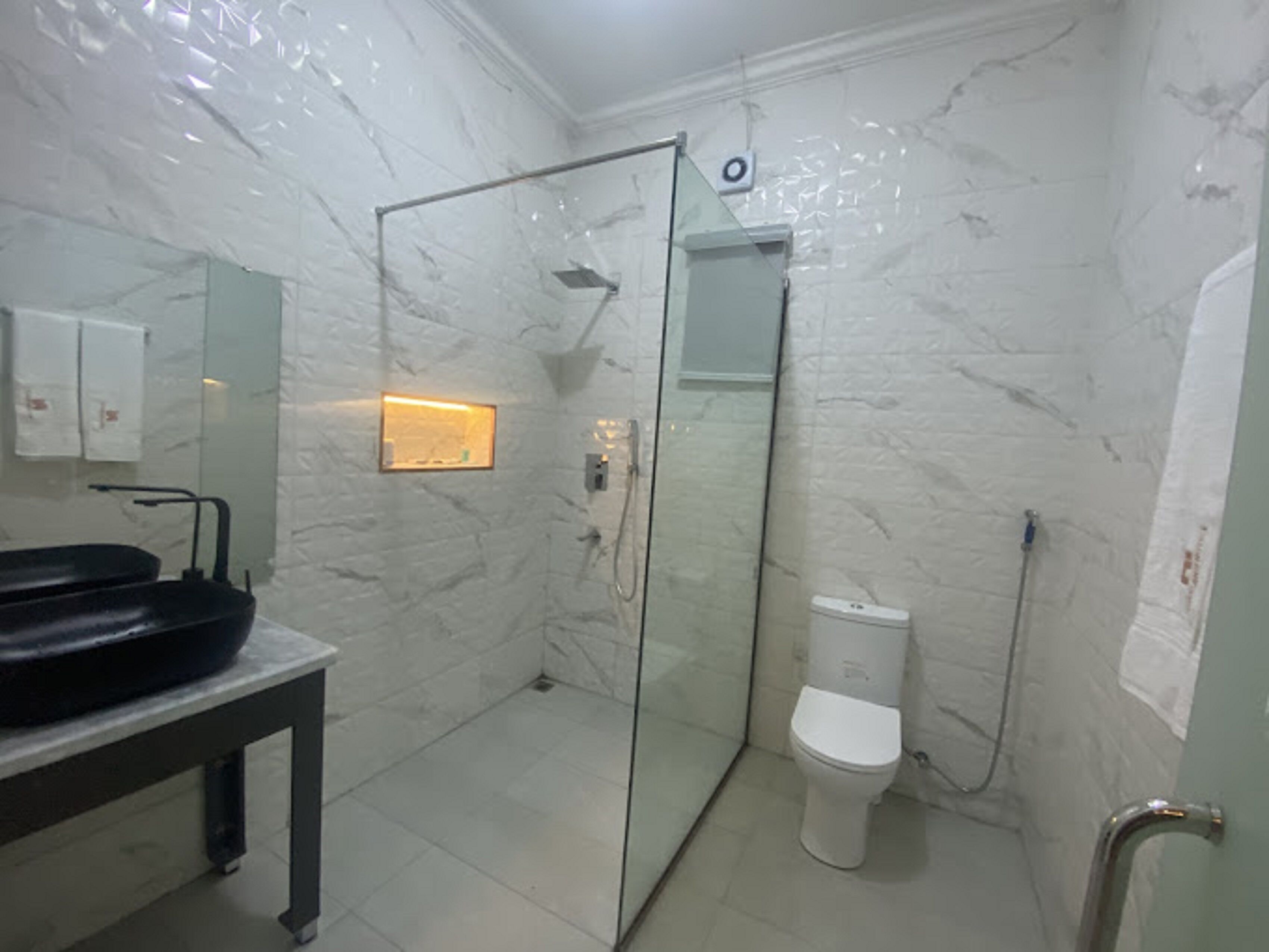 A bathroom with a glass-enclosed shower, a white toilet, and a black sink.