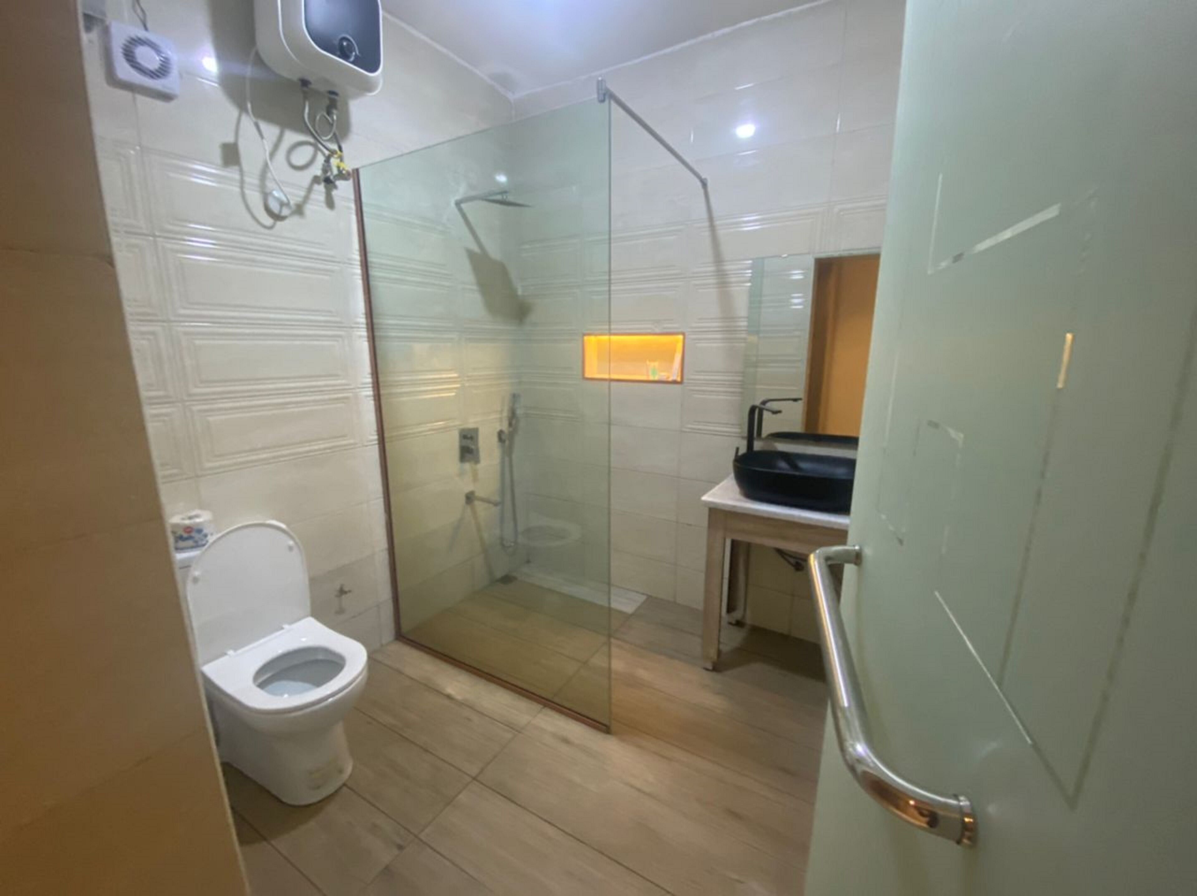 Une salle de bain dotée d’une douche à parois de verre, de toilettes et d’un lavabo avec un receveur noir.