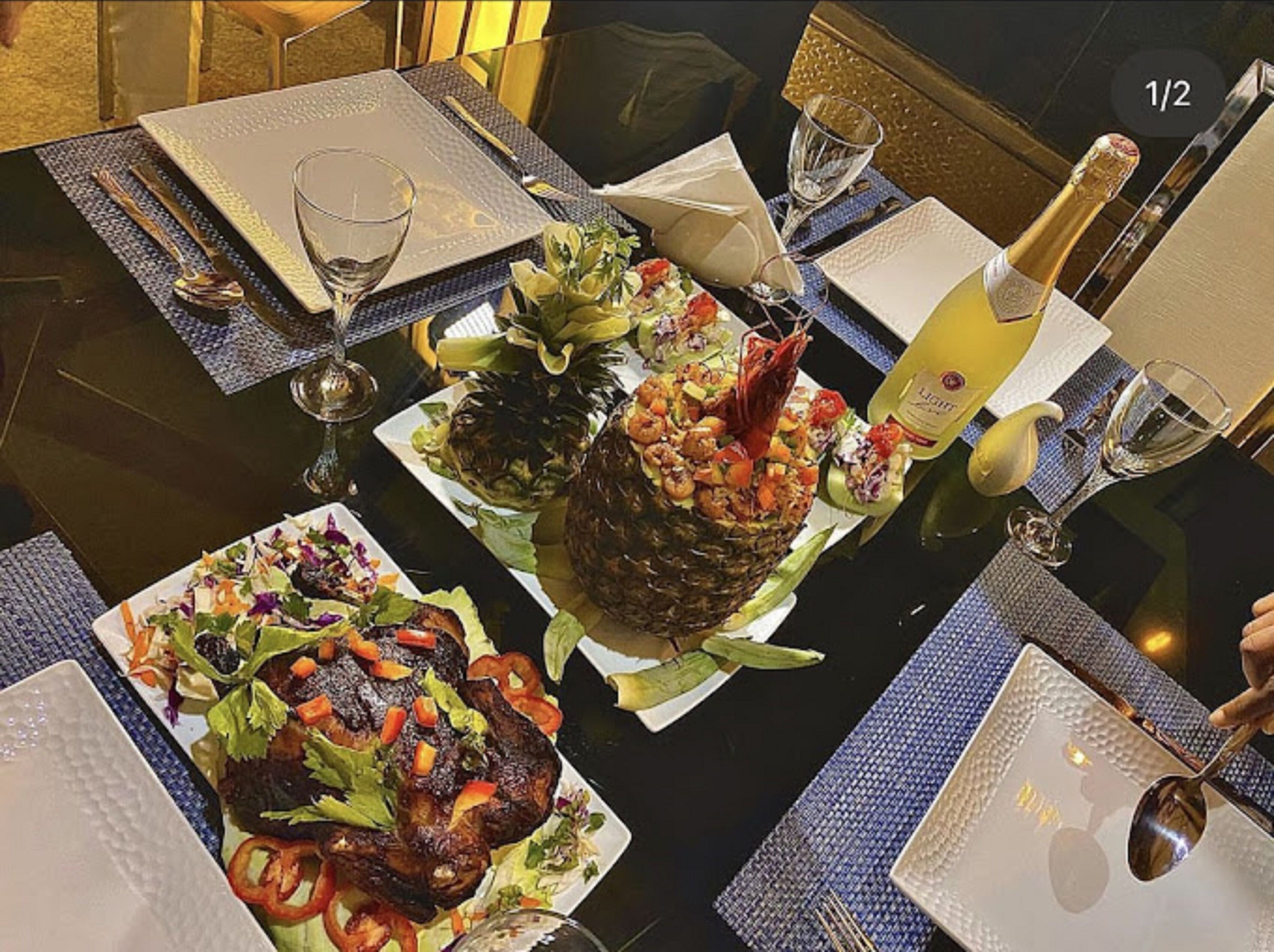 A dining table set with plates of food, wine glasses, and a bottle of champagne.