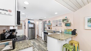 Una cocina con encimeras de granito, electrodomésticos de acero inoxidable y una isla central con taburetes.