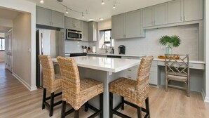 Cocina moderna con armarios grises, una isla blanca y sillas de mimbre.