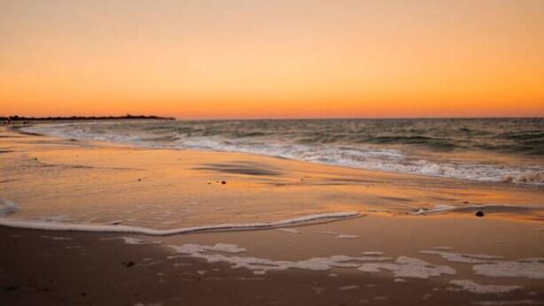 A beach at sunset with waves gently lapping the shore. - Renovated-Beach Bungalow-Walk to Beach (Hampton)