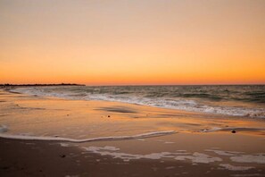 A beach at sunset with waves gently lapping the shore.
