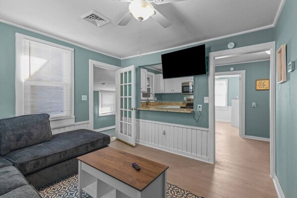 A living room with a gray sofa, a wooden coffee table, and a TV mounted on the wall.