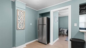 A kitchen with teal walls, a stainless steel refrigerator, and a wooden floor. - Renovated-Beach Bungalow-Walk to Beach (Hampton)