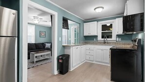 A compact kitchen with white cabinets, a black stove, and a stainless steel refrigerator. - Renovated-Beach Bungalow-Walk to Beach (Hampton)