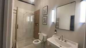 A modern bathroom with a walk-in shower, toilet, and sink. - Stylish apartment above popular traditional village pub! (Saint Brides Major)