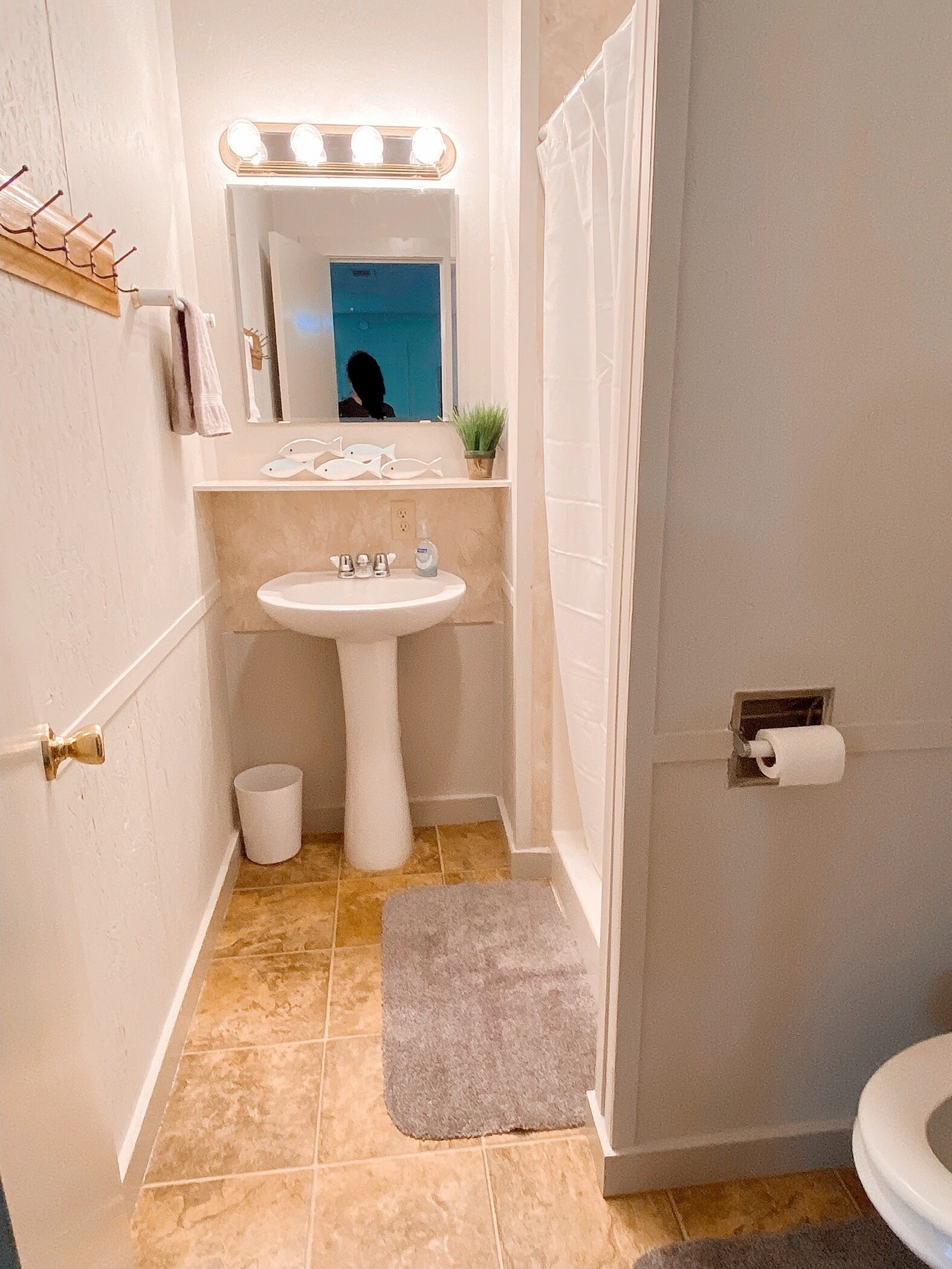 Et lille badeværelse med vask, spejl og toilet.