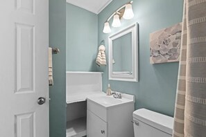 Bathroom features a sink, toilet, and mirror with a wall-mounted light fixture.