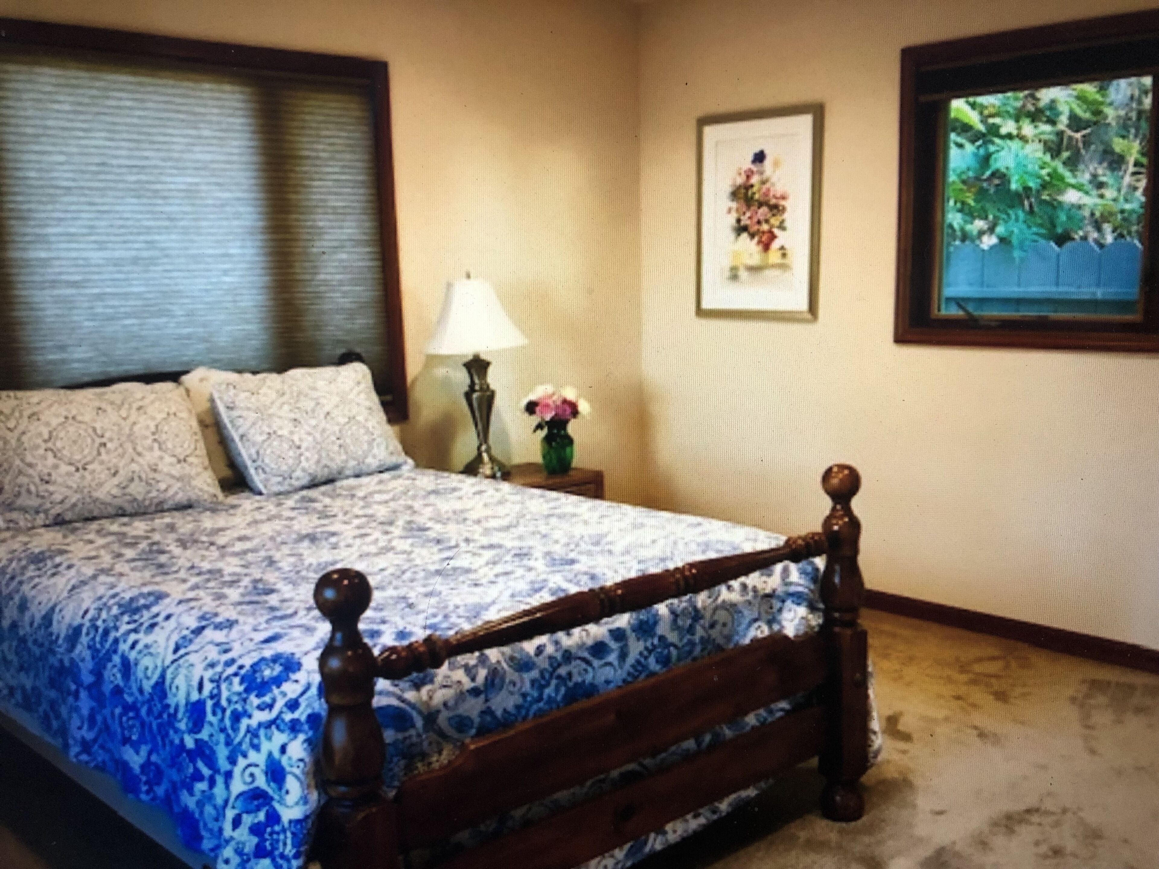 Un dormitorio con una cama, una mesita de noche, una lámpara y un cuadro en la pared.