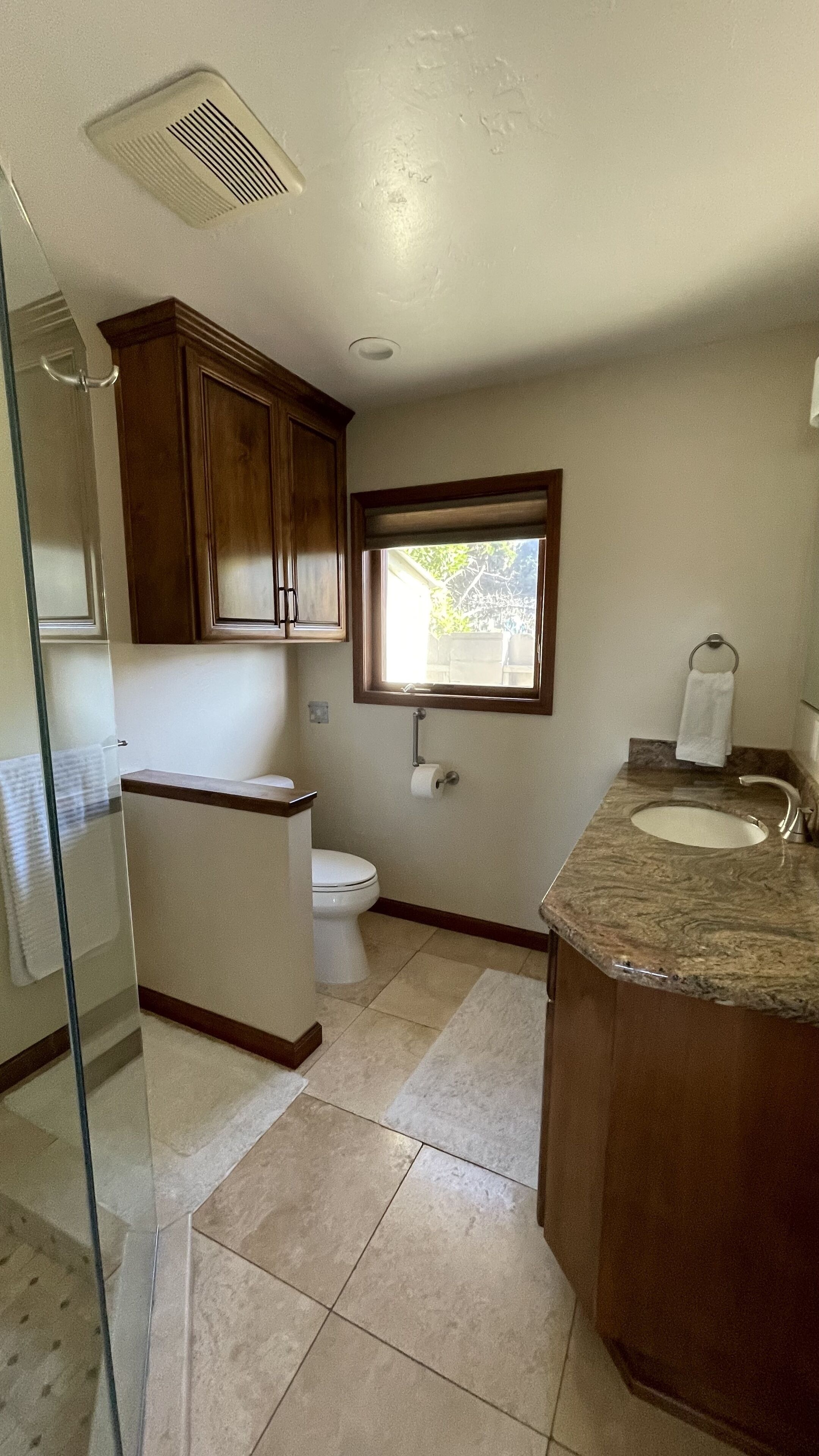 A bathroom with a toilet, sink, and window.