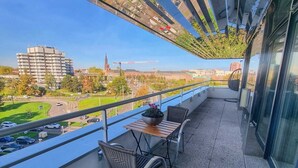 A balcony with a view of a cityscape, including buildings and a church. There are two metal chairs and a small table with a potted plant. - Exceptional apartment in Strasbourg (Strasbourg)