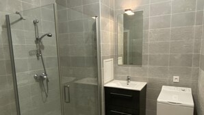 A modern bathroom with a glass-enclosed shower, a white sink, and a compact washing machine. - Exceptional apartment in Strasbourg (Strasbourg)