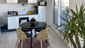 A modern kitchen with white cabinets, a built-in microwave, and a dining area with a round table and two chairs. - Exceptional apartment in Strasbourg (Strasbourg)