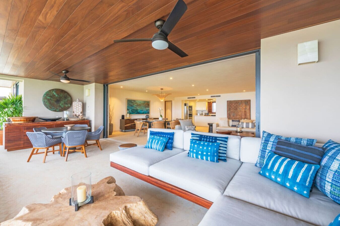 A modern living room with a large sofa, a dining area, and a kitchen in the background.