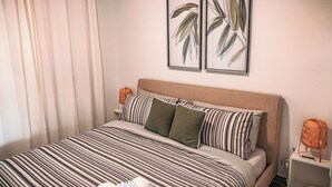 A neatly made bed with striped bedding, a headboard, and two wall-mounted plant prints. - 3 BR Residence w. Private Terrace + Rooftop (San Juan)