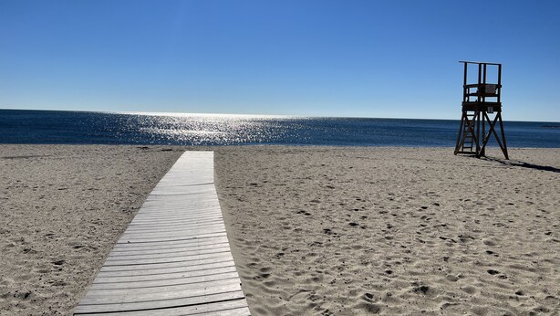 Une plage avec une promenade en bois menant à un poste de surveillance des sauveteurs.
