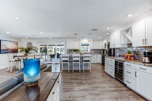A modern kitchen with white cabinets, a dining area with a table and chairs, and a large window providing natural light.