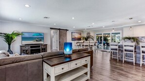 A spacious living area with a sofa, a coffee table, and a TV. There is a dining area with chairs and a table. - Waterfront, Heated Pool, Dive In Theater,Family Friendly (Cape Coral)