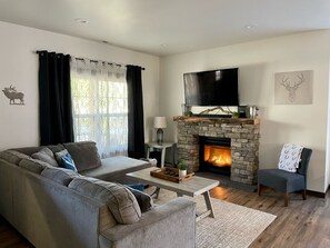 Relax in this inviting living room with a stone fireplace, flat-screen TV, and comfortable sofa.