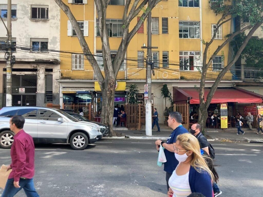 A street scene with pedestrians, a parked car, and buildings with commercial establishments.