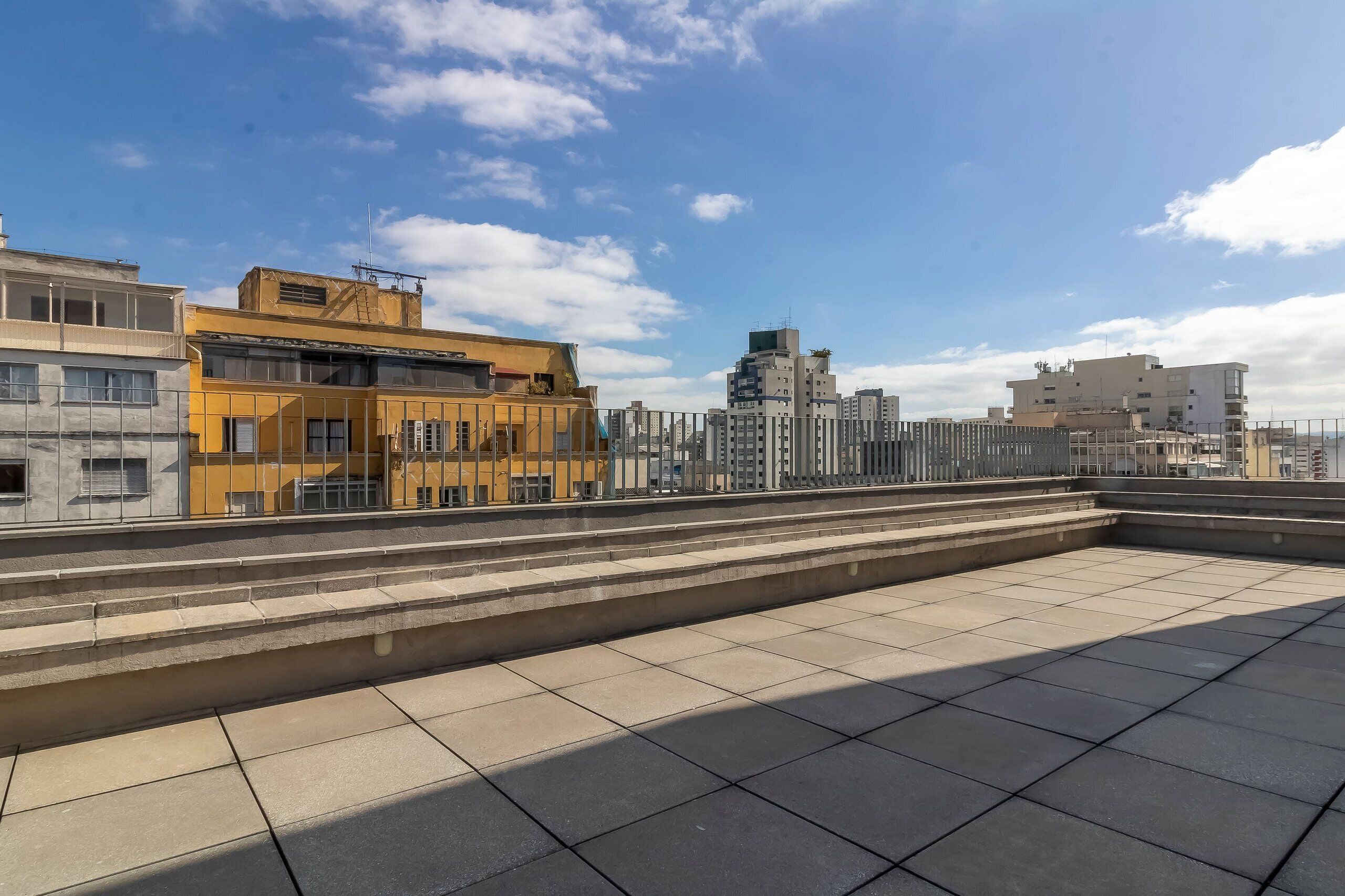 Une terrasse sur le toit, dotée d’un sol carrelé et d’une rambarde en métal.