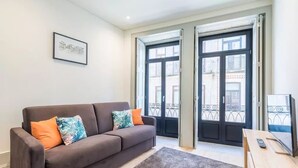 Een moderne woonkamer met een grijze bank, een klein houten tafeltje en een lijst met een foto aan de muur.