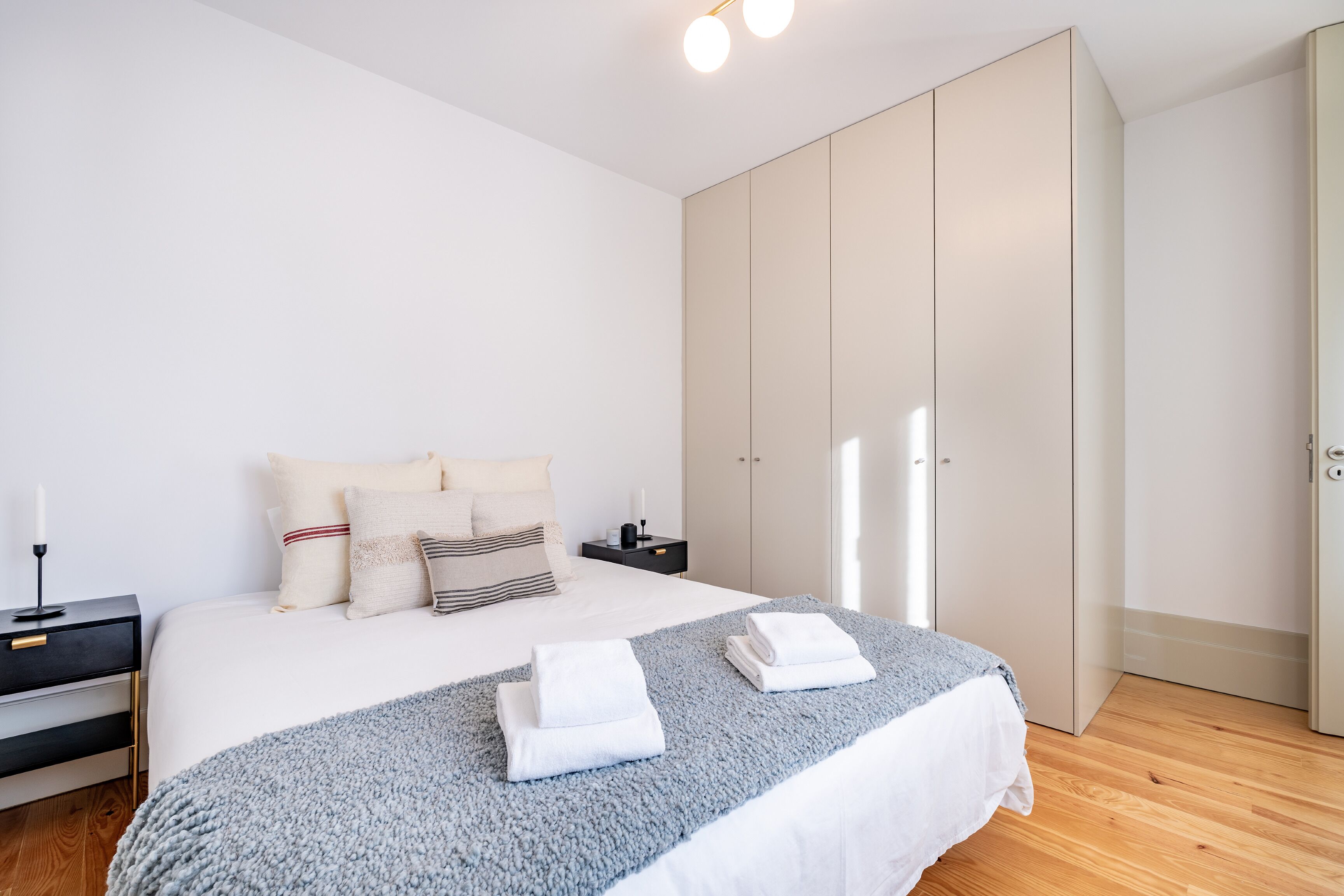 Un dormitorio moderno con una cama grande, un armario y una mesita de noche.