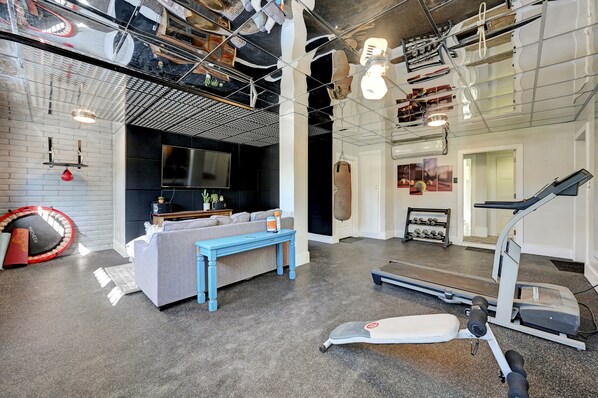 A modern gym with a treadmill, weights, and a punching bag.