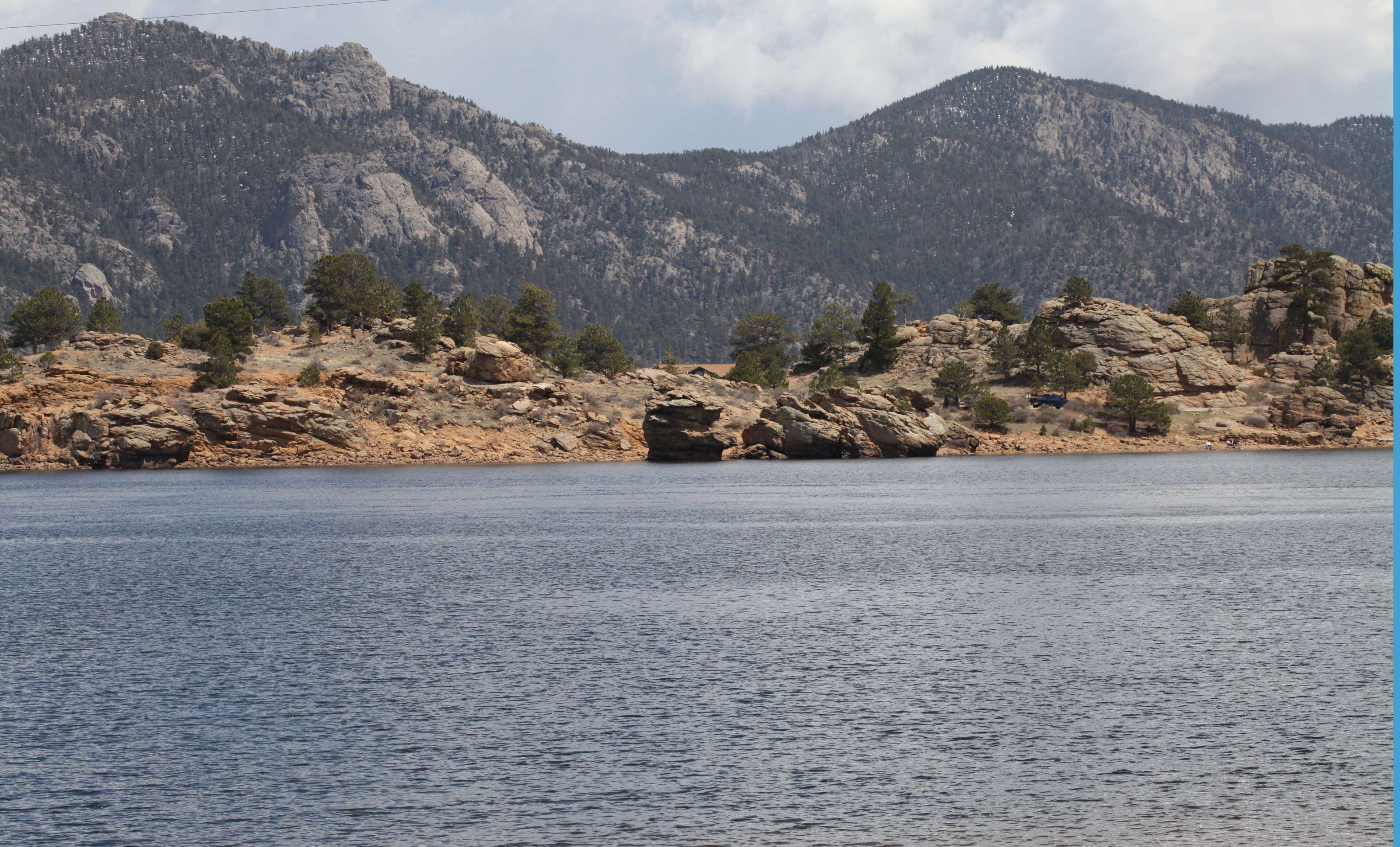 Un lac aux rives rocheuses, avec des montagnes en arrière-plan.
