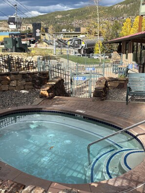 Una piscina con borde de piedra y escalera de metal.