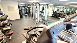 A gym with various exercise equipment, including treadmills, weight machines, and free weights.