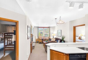 A modern kitchen with a built-in dishwasher, a dining area with a table and chairs, and a living room with a sofa and a coffee table. - FRONT ROW Ski-In Ski-Out Updated 2BR Slopeside with Gondola, Slope & Base VIEWS! (Winter Park)